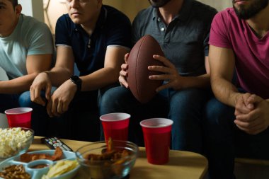 Erkek arkadaşlar TV 'de heyecanlı bir futbol maçı izlerken evde toplanıp atıştırmalık ve içeceklerin tadını çıkarıyorlar.