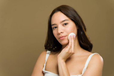 Güzel genç bir kadın makyajını silmek için pamuk pedi kullanıyor, cilt bakımını ve güzellik uygulamalarını gösteriyor.