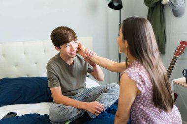 İspanyol anne, küçük oğluna sevgi ve şefkat gösteriyor. O utancından kaçmaya çalışırken onun yüzünü okşuyor.