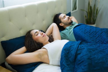 Huzurlu bir çift yatakta uzanıyor, huzurlu bir sabah geçiriyorlar, rahatlama ve yakınlık gösteriyorlar.