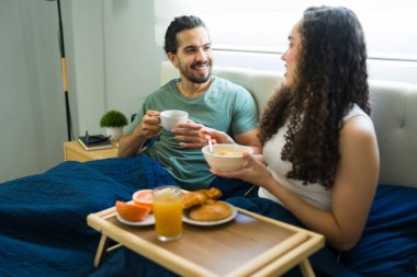 Hafta sonu evde kahvaltı yaparken gülümseyen ve konuşan genç bir çift.