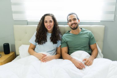 Modern ve parlak bir yatak odasında dinlenirken İspanyol çift birlikte vakit geçiriyorlar.