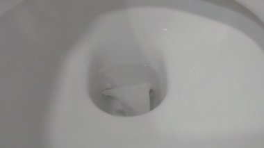 Tuvaletteki sifonu çekme manzarası. Su tasarrufu. Sifonu çek. Su akışı. Beyaz bir tuvalette sifonu çekmek.