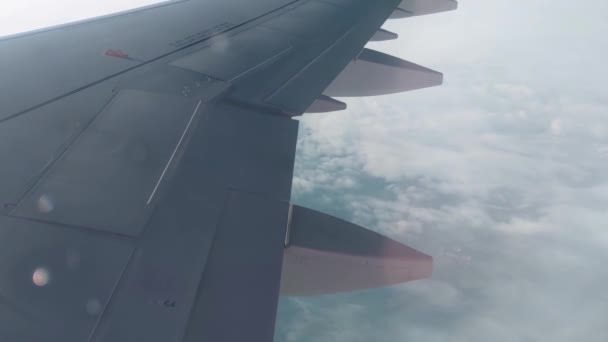 飛行機の窓からの眺め 飛行機は曇りの日に雲の上を飛ぶ 雲の中から地面が見える 安全かつ迅速な輸送モード — ストック動画
