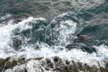 Turkuaz okyanus suyu. Kayalara çarpan suyun havadan görünüşü. Ada bir volkanik patlamanın sonucudur.