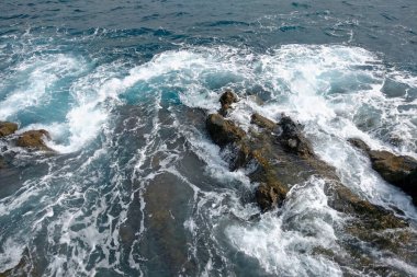 Adanın kayalarını ve kıyılarını yıkayan okyanus ve denizin güzel turkuaz suyunun manzarası. Doğa arkaplanı