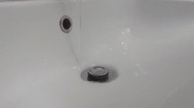 Close-up on a washbasin and a faucet from which water flows. Water saving. Saving resources. The concept of expensive water