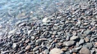 Transparent clean water rolls onto the shore of the beach. Rocky beach