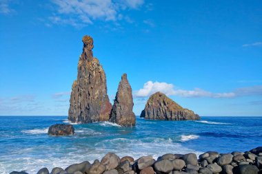 The waves of the ocean wash the rocks in the water. The background of nature