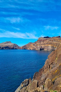 Beautiful rocky coast of Madeira island, Portugal. Vacation on the island. Red earth and mountains