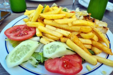 Masada bir tabak taze sebze ve patates var. Hızlı ve lezzetli yemekler.