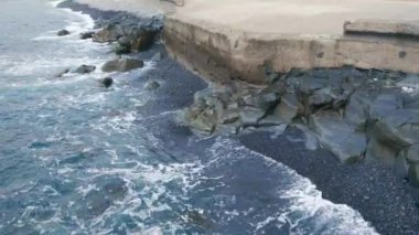 Bir adanın ya da anakaranın beton kıyısı. Tsunamilere ve büyük dalgalara karşı koruma. Okyanus veya deniz dalgaları kıyıya ve kayalara çarpar.