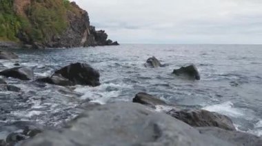 Okyanusun dalgaları kıyıya vuruyor ve sahildeki taşlar...