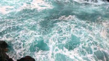 Güzel turkuaz su kayalara çarpar, yüksekten.