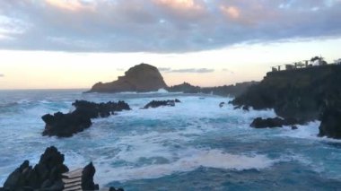 Okyanusun dalgaları kayalıklarda kırılıyor. Doğanın gücünün manzaralı görüntüsü. Adanın kıyısında gün batımı