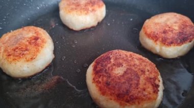 Peynirli kekler tavada kızartılır ve bir spatulayla çevrilir. Ev yapımı yemek. Hafif ve lezzetli bir kahvaltı.