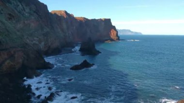 Okyanusun dalgaları kayalık kıyılara çarpar.