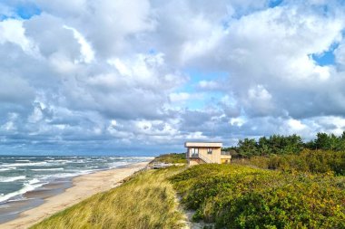 Deniz kenarında yazlığı olan küçük bir sahil manzarası.