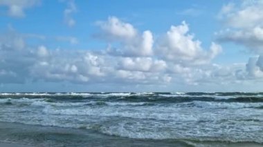 Büyük deniz dalgaları kumlu sahilde yuvarlanıyor..