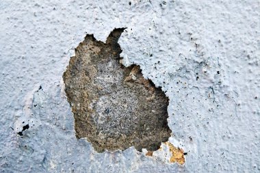 A crack has formed on a concrete wall, revealing a rusted surface underneath. The rust has spread outwards, showing signs of decay and neglect. clipart
