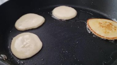 Pancakes cooking on a nonstick skillet one pancake is golden brown while others are batter. the image illustrates breakfast preparation, food texture, and culinary techniques, suitable for food blogs