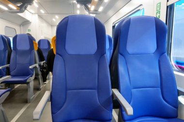 Rahat bir seyahat deneyimi için tasarlanmış mavi koltuklu modern tren iç tasarımı. Oturma düzeni, uzun yolculuklar için ideal olan ferahlığı ve ergonomiyi vurgular. Pencereler doğal ışık sağlıyor, davetkar atmosferi arttırıyor..