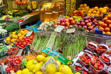 Bolonya, İtalya, 15 Mayıs 2024: Bir çiftçi pazarında canlı bir taze meyve ve sebze gösterisi, renkli domates çeşitleri, kuşkonmaz, limon, çilek ve daha fazlası sergileniyor. Fiyat ve kaynağı belirten etiketler görünür, bir dalgıç sunar