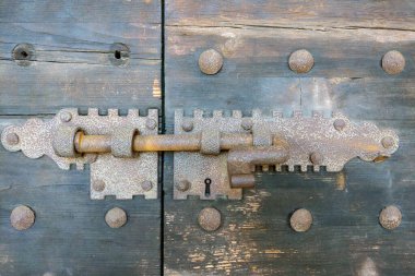 Kaliteli demir kilit ve cıvata mekanizması olan eski ahşap bir kapı. Bu yakın plan vurgular karmaşık metal işleri ve eski dokular, mimari çalışmalar, tarihsel referanslar veya tasarım ilhamı için ideal.