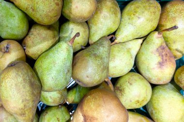 Taze yeşil armutların yakın çekimlerinde dokuları ve doğal renkleri gösteriliyor. Bu resim pazarların, besinlerin ve sağlıklı beslenme kavramlarının, taze tarım ürünlerinin ve çeşitli mutfak uygulamalarının tanıtımı için idealdir..