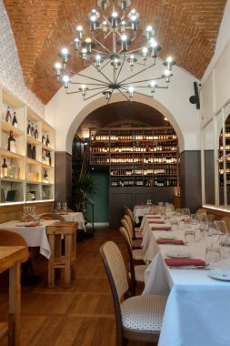 Florence, Italia, 10 Mayıs 2024: Kemerli tuğla tavan, sofistike avize ve geniş bir şarap sergisi içeren şık bir restoran iç mimarisi. Yemek odası beyaz masa örtüleri, cam örtüler ve ahşap mobilyalarla dolu.