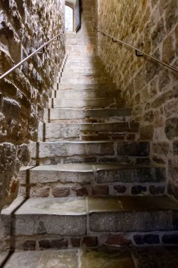 Kadim taş merdiven, bir ortaçağ binasının güneş ışığıyla aydınlatılmış penceresine doğru yükseliyor. Merdivenler ve taş duvarlar tarih ve mimari duygusu yayıyor, zamanın eskimiş, kırsal çekiciliği ve ustalığı..
