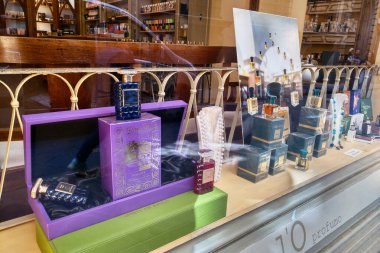 Florence, Italia, 11 Mayıs 2024: Lüks bir mağazada çeşitli lüks parfümlerin sergilendiği zarif bir mağaza. Renkli şişeler ve ambalajlar cam bir rafta sergileniyor. Karmaşık tasarımlar, markalaşma unsurları, zenginlik ve üst düzey mağaza ürünleriyle.