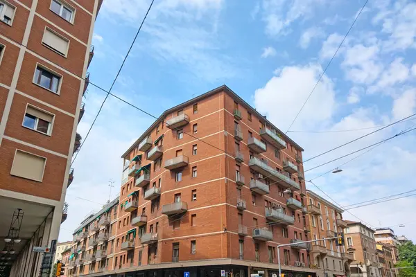 stock image Bologna, Italy, May 16, 2024: Urban residential building featuring distinct red brick facade, multiple balconies, and an angular design. captured from a low angle against a clear sky, architectural details and city infrastructure elements, perfect fo