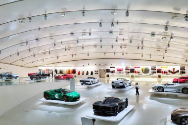 Modena, İtalya, 12 Mayıs 2024: Çeşitli klasik ve spor arabaların sergilendiği modern araba galerisi. Geniş, iyi ışıklandırılmış iç mekan parlak tasarım elementleri, lüks araçların sergilenmesi ve görsel olarak çekici bir ortam sağlanması