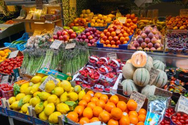 Bolonya, İtalya, 19 Mayıs 2024: Canlı pazar, portakal, kavun, limon, domates ve kuşkonmaz gibi çeşitli taze meyve ve sebze çeşitlerini sergilemektedir. El yazısı fiyat etiketleri geniş bir selekti ile hareketli, canlı bir atmosferi tasvir eder