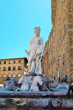 Florence, Italia, 11 Mayıs 2024: Neptün 'ün heykeli Floransa, İtalya' daki tarihi bir çeşmede sergilendi. Rönesans binaları ve açık mavi gökyüzü bu ikonik Avrupa turistik cazibesinin ihtişamını ve zamansız güzelliğini artırır