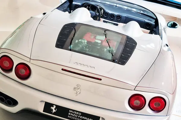 stock image Modena, Italy, May 12, 2024: Elegant rear view of a luxury sports car displayed at museo enzo ferrari. featuring a sleek design, the convertible showcases its powerful engine through a transparent cover, emphasizing performance and style. ideal for a