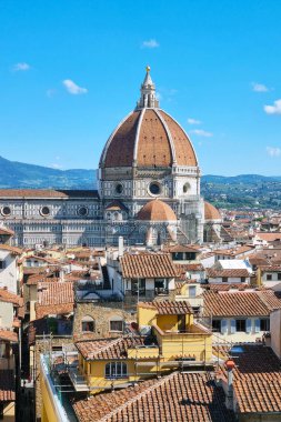 Floransa, İtalya, 11 Mayıs 2024, Santa Maria del Fiore Katedrali 'nin ikonik kubbesine ev sahipliği yapan Floransa, İtalya' nın canlı şehir manzarası. Ön planda geleneksel İtalyan çatıları, mavi gökyüzü ve yuvarlanan tepeler karşısında sergileniyor.