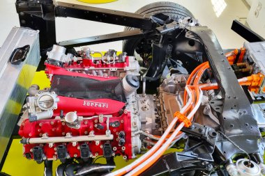 Modena, İtalya, 12 Mayıs 2024: Ferrari otomobil motoru ve şasisi, karmaşık mekanik bileşenler ve mühendislik mükemmelliği sergiliyor. Kırmızı ferrari motor bloğu metalik şasiyle ve renkli kablolarla çelişiyor.