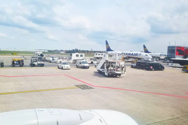 stock image Bologna, Italy, May 18, 2024: A busy airport apron showing ground support equipment and vehicles servicing ryanair planes. passenger boarding bridges and support trucks are visible, with a clear view of planes preparing for boarding under a partly cl