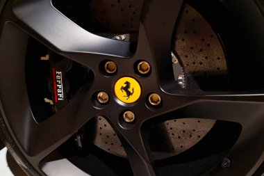 Modena, İtalya, 12 Mayıs 2024: Pürüzsüz siyah alaşımlı jantlı lüks bir spor araba tekerinin yakın plan görüntüsü ve merkez kapağında ikonik sarı ferrari logosu. Yüksek performanslı fren kalibreli ferrari de görülebilir.