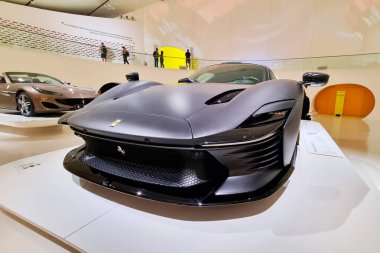 Modena, İtalya, 14 Mayıs 2024: Gösterişli, mat siyah ferrari spor araba sergisi başka bir lüks aracın yanında. İç mekan dekorları cilalanmış zeminler, yüksek tavanlar, ve sergilenmiş sergiler, son teknoloji tasarım ve otomotiv