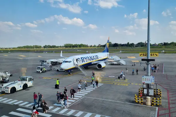 Brüksel-Charleroi, Belçika, 24 Haziran 2024: Bir ryanair uçağı, açık ve mavi bir gökyüzü altında, çok sayıda yolcuyla birlikte havaalanı pistinde bulunuyor. Yer ekibi ve destek araçları kalkış için uçağı hazırlayın.