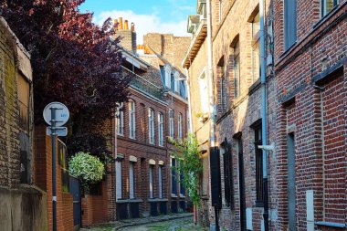 Lille, Fransa, 23 Haziran 2024: Tarihi bir Avrupa şehrinde kırsal kırmızı tuğla binalarla çevrili tuhaf bir kaldırım taşından sokak manzarası. Sokakta geleneksel mimari sergileniyor.