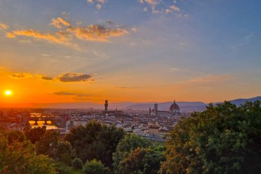 Floransa, İtalya, 11 Mayıs 2024 Floransa: Floransa üzerinde görkemli bir gün batımı, ikonik ikonik ikilisi ve akan Arno nehri ile tarihi şehir siluetini gözler önüne seriyor. Bereketli yeşillik, canlı, bulutlarla çizilmiş Toskana manzarasının nefes kesici manzarasını çerçeveler. 