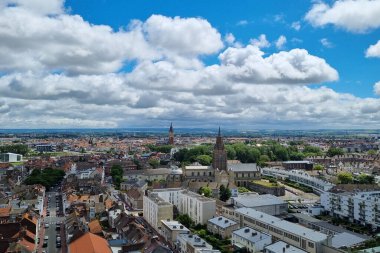 Calais, Fransa, 22 Haziran 2024: Avrupa 'nın önde gelen kilise kuleleri ve geleneksel ve modern mimarinin bir karışımının yer aldığı tarihi bir kentinin manzaralı fotoğrafı. Mavi gökyüzünün altında geniş bir ufuk çizgisi ve dağınık bulutlar şehrin
