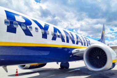 Wroclaw, Polonya, 18 Haziran 2024: Ryanair uçakları, kısmen bulutlu mavi bir gökyüzüne karşı görünür jet motoru ve markalı pistte park halindedir. Ticari uçakların seyahat temaları için uygun ölçeği ve modern tasarımını vurguluyor, aviati