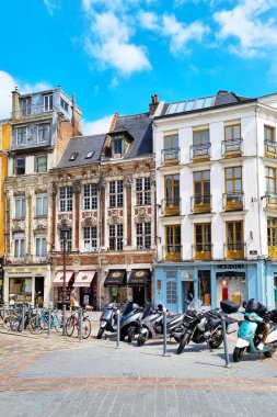 Lille, Fransa, 23 Haziran 2024: Parlak mavi bir gökyüzünün altında dizilmiş tarihi Avrupa mimarisi, klasik cepheli, motosikletli ve bisikletli binaların yer aldığı canlı sokak sahnesi. Seyahat ve şehir tasarımı için ideal