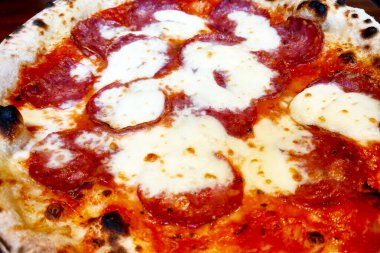 Yakından bakınca taze pişmiş pepperonili pizzanın içinde bol miktarda pepperoni ve erimiş peynirin çıtır çıtır olduğu görülüyor. Mönü tasarımları, yemek blogları, reklamlar ve promosyon malzemeleri için ideal İtalyan mutfağı.