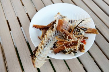 Tahta bir masada duran balık kemikleri ve kalıntılar, çevre dostu uygulamaları, sürdürülebilir yaşamı ve sıfır atığı sembolize ediyor. Bu resim, sürdürülebilirliği, çevresel bilinci savunan yazılar, gönderiler ve tasarımlar için kullanılabilir.